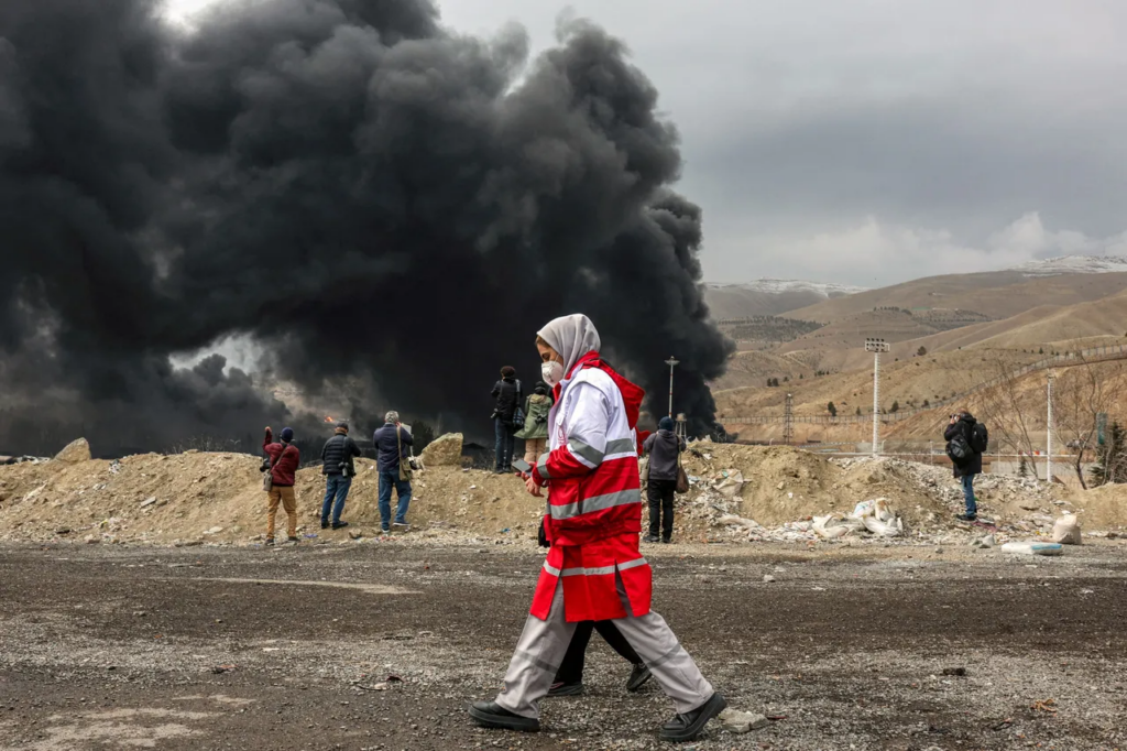 Une femme membre du Croissant-Rouge iranien près de la raffinerie de pétrole de Shahran touchée par une frappe, au nord-ouest de Téhéran, le 8 mars 2026. ©AFP