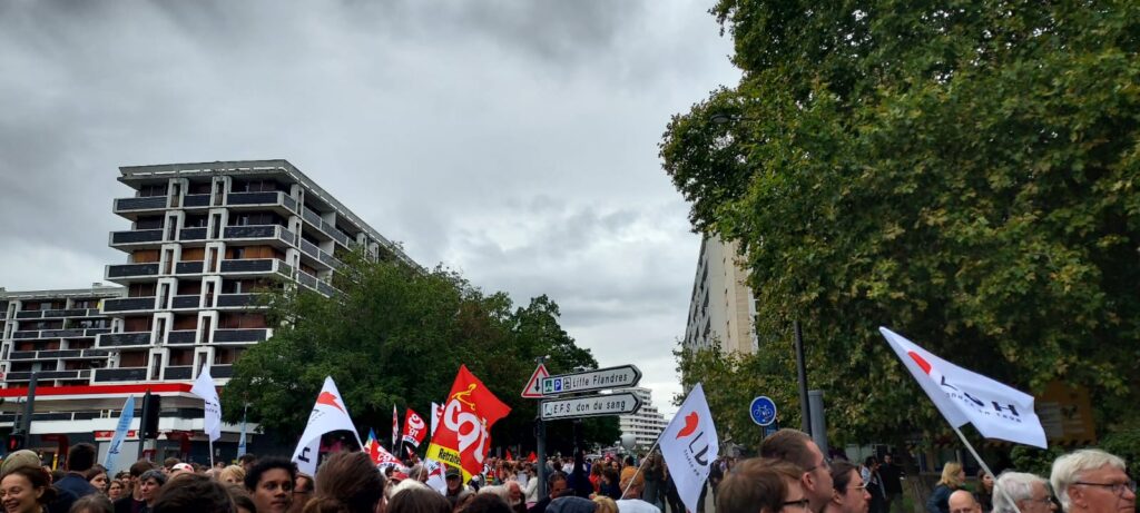Photo de drapeaux LDH au dessu de la foule a la manifestation.